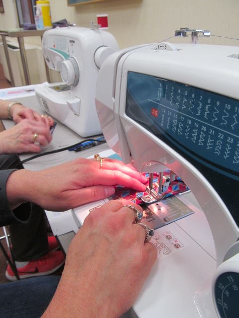 close up of hands working on a project at a sewing machine at Rock Island Public Library