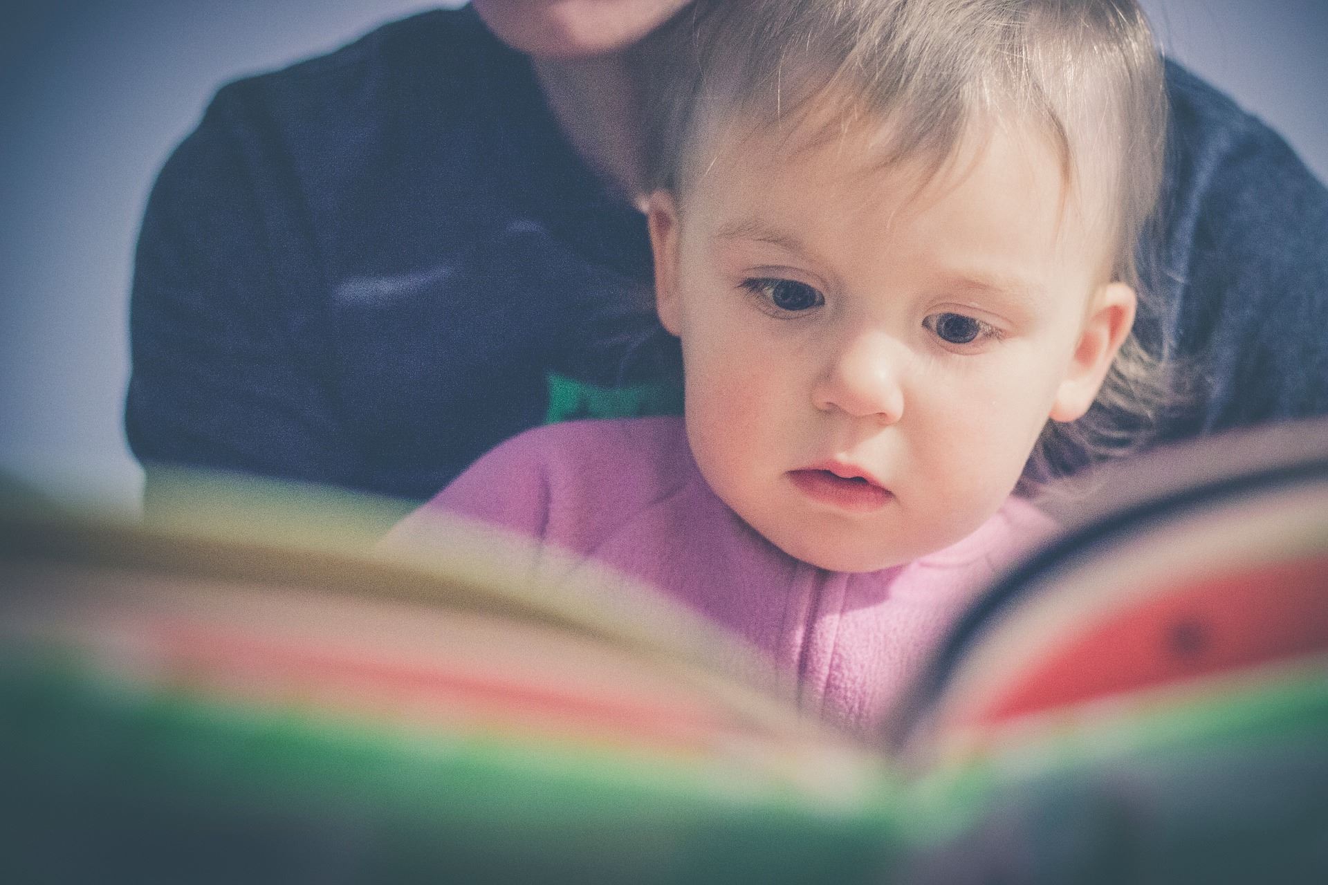 soft focus photo of baby being read a book