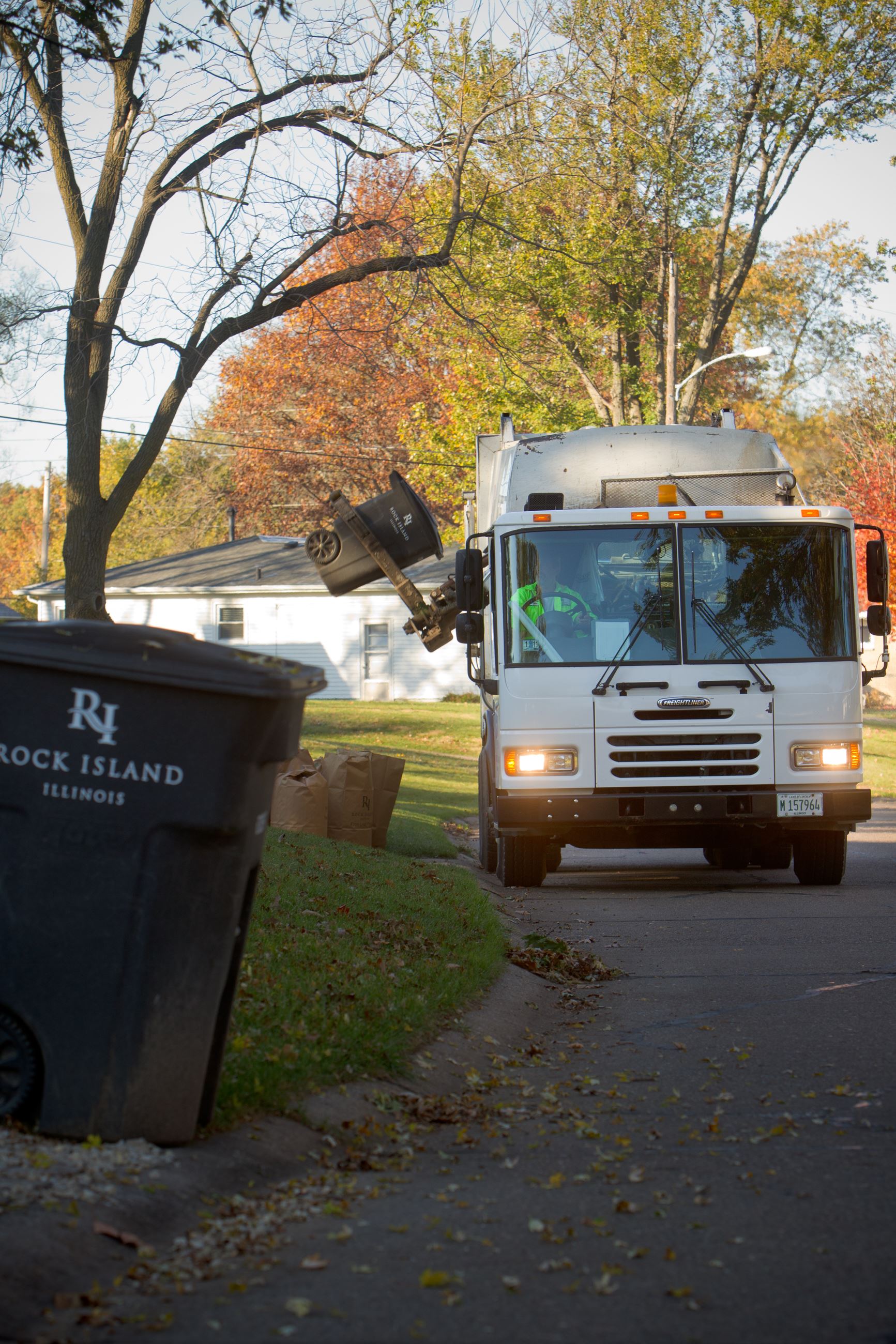 Refuse truck and cart in neighborhood during leaf bag collection